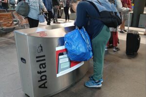 Eine Frau durchsucht einen Abfalleimer, symbolisiert soziale Not und Altersarmut in Deutschland.