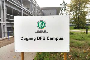 Bernd Neuendorf, stolzer DFB-Präsident, feiert seine Wiederwahl mit Delegierten im Hintergrund.