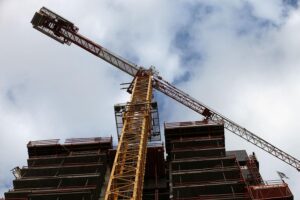 Moderne Baustelle mit Wohnungsbaukränen und Bauarbeitern, die den Anstieg an Baugenehmigungen symbolisieren.