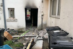 Feuerwehr im Einsatz bei Brand in Dortmunder Mehrfamilienhaus, Bewohner evakuiert, Rauchentwicklung sichtbar.