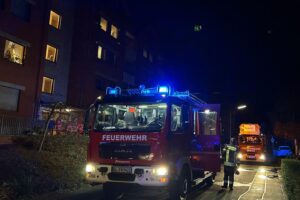 Feuerwehr Rösrath löscht Brand, rettet Person aus Mehrfamilienhaus, mit Einsatzkräften im Einsatz.