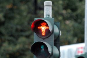 Rote Fußgängerampel mit verletztem Fußgänger und Fahrzeug im Hintergrund, Unfallstelle in Berlin.