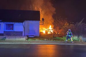 Brand eines Holzschuppens in Wittlich, Feuerwehr verhindert Übergriff auf Wohnhaus, Ermittlungen laufen.