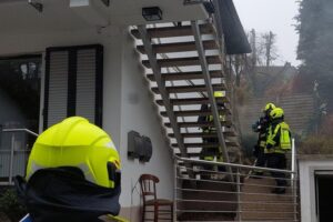 Feuerwehr im Einsatz nach Küchenbrand; Einsatzkräfte löschen Rauch und retten Bewohner.