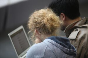Frau und Mann am Computer, diskutieren über Schuldenberatung und Online-Händlerproblematik.