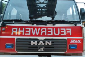Feuerwehrfahrzeuge und Einsatzkräfte löschen ein abgebranntes Mehrfamilienhaus in Laudenbach.
