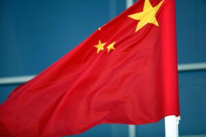 Fahne Chinas vor Hintergrund, der die Repression der Uiguren symbolisiert und Menschenrechtsverletzungen andeutet.