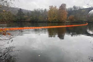 Ölschleier auf Gewässer, Feuerwehr im Einsatz, Ölsperre, Kanu-Club, Einsatzkräfte, Umweltgefahr.