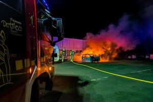 Pkw-Brand in Detmold gefährdet Wohnwagen Brennender Pkw mit Feuerwehr im Einsatz, Wohnwagen gefährdet, aber unbeschädigt.