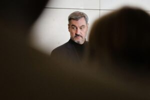 Markus Söder in München, umgeben von kritischen SPD-Politikern, diskutiert über Energiezukunft.