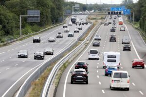 Sanierende Autobahnbrücke mit Bauarbeitern und schwerem Gerät im Fokus der Verkehrsinfrastruktur.