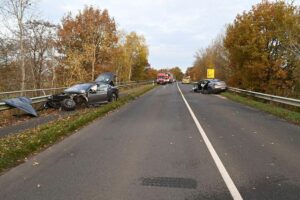 Verkehrsunfall mit Feuerwehr und Rettungskräften, beschädigte Fahrzeuge und gesperrte Straße.