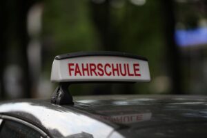 Unbekannte schießen auf Fahrschule in Berlin-Reinickendorf Fahrschule mit Ausbilder, Schüler im Auto, Symbol für sichere und bezahlbare Fahrausbildung.