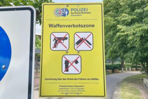 Grafik einer Waffenverbotszone mit Symbolen für Sicherheit und verbotene Waffen im Hintergrund.