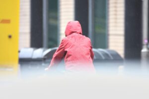 Mann mit Kapuze vor grauem, nebligen Wetter, symbolisiert trübes, wechselhaftes Klima in Berlin.