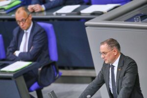 Zwei Politiker stehen zusammen, symbolisieren die Union, während Umfragen zur Bundestagswahl thematisiert werden.
