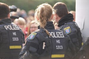 Polizisten nehmen mutmaßliche Einbrecher fest, während Anwohner aufmerksam aufmerksam sind.