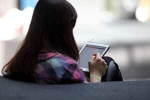Frau mit Tablet diskutiert Klarnamenpflicht und digitale Verantwortung in sozialen Medien.