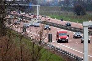 Autobahn mit Unfallstelle, Polizei und Rettungswagen, beschädigte Fahrzeuge, gesperrte Fahrbahn.
