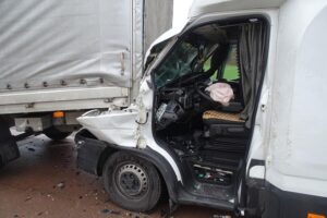 Unfallstelle mit verunglücktem LKW, beschädigten Fahrzeugen und Einsatzkräften der Feuerwehr.