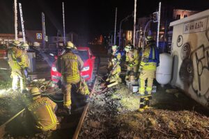 Auto auf Gleisen, Feuerwehr bei Bergung, Bahnverkehr unterbrochen, Dunkelheit, Unfallstelle dokumentiert.
