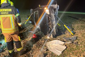 Ein Feuerwehrmann befreit einen verletzten Autofahrer aus einem verunfallten Fahrzeug im Gleisbett.