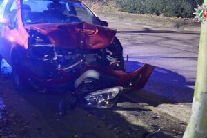 Roter Opel Corsa mit Totalschaden nach Kollision mit Straßenlaterne auf Gehweg in Oberhausen.