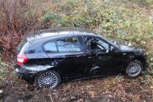 Unfallfahrzeug im Straßengraben, Polizei und Rettungsdienst im Einsatz, verletzte Fahrerin wird versorgt.