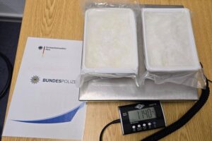 Gesetzeshüter zeigen sichergestellte Drogenpakete auf einer Tischfläche, umgeben von polizeilicher Ausrüstung.