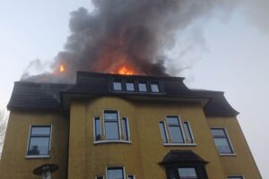 Dachstuhlbrand in Wetter (Ruhr) mit Feuerwehr im Einsatz, Flammen und Rettungswagen sichtbar.