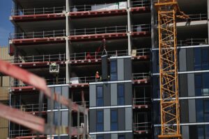 Baustelle mit Bauarbeitern und Wohngebäuden, symbolisiert den Wohnungsbau in Deutschland.