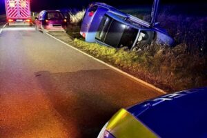 Unfallauto im Graben; Ersthelfer helfen verletztem Fahrer auf Jalan. Polizei ermittelt.