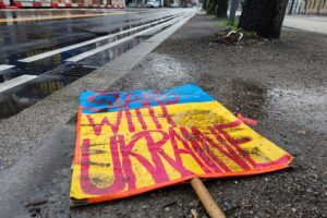 Ein Schild "Stand with Ukraine" auf dem Boden, symbolisiert Unterstützung und Besorgnis über den Konflikt.