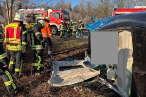 Unfallfahrzeug zwischen Bäumen, Feuerwehr bei der Rettung, Dach wurde entfernt, Erste-Hilfe-Einsatz.