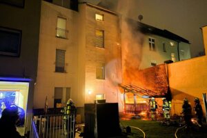 Brand im Mehrfamilienhaus: Feuerwehr im Einsatz, verrauchte Treppenräume, keine Verletzten, Anwohner evakuiert.