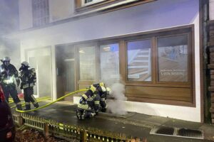 Feuerwehr im Einsatz: Löschangriff an einem Wohn- und Geschäftshaus mit Rauchentwicklung im Keller.