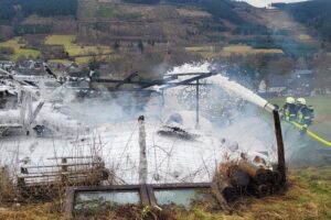 Vollständig abgebrannte Scheune, Feuerwehr im Einsatz, Traktor und Stroh im Inneren.