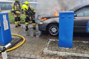 Ein Feuerwehrteam löscht brennenden Opel in Detmolder Straße, Verkehr gesperrt.