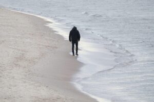 Mann alleine am Strand, symbolisiert Einsamkeit in einer zunehmend digitalen Welt.
