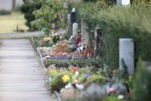 Friedhof mit Grabsteinen, umgeben von Grabschmuck. Hinweis auf Diebstahl und Polizeiarbeit.