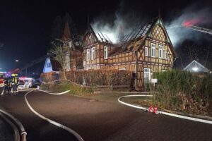 Ein brennendes Fachwerkhaus in Rotenburg, eingerahmt von Feuerwehrfahrzeugen und Rauch.