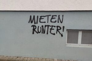 Graffiti mit der Aufschrift "Mieten runter", symbolisiert den Kampf für erschwinglichen Wohnraum.