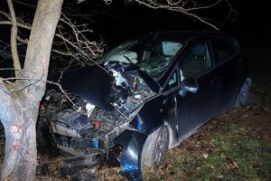 Verkehrsunfall mit stark beschädigtem Auto, Einsatzkräfte und verletzte Jugendliche.
