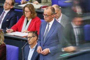 Friedrich Merz diskutiert im Bundestag, während Vertreter der Mieterinteressen abwesend wirken.