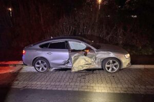 Zwei Unfallfahrzeuge auf Parkplatz nach mutmaßlichem Autorennen, Polizei und Verletzte vor Ort.