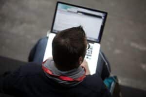 Computernutzer in einer modernen Büroumgebung, Symbole für Digitalisierung und Verwaltung sichtbar.