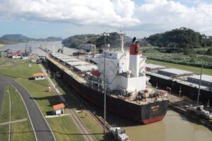 Frachtschiff im Panama-Kanal, symbolisiert den globalen Handel und wirtschaftliche Herausforderungen.