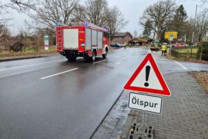 Ölspur auf Straße, Feuerwehr im Einsatz, Warnschilder und Sandbarrieren sichtbar.