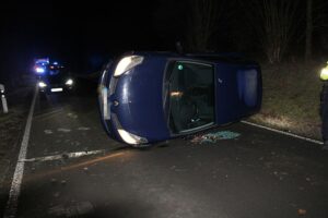 Verunfallter Renault auf glatter Straße, Rettungsdienst und Polizei im Einsatz, Fahrzeug im Böschungsbereich.