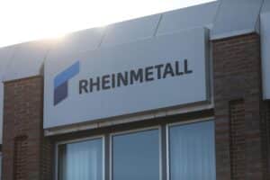 Rheinmetall-Logo mit Symbolen für Autozulieferung und Rüstungsindustrie, Darstellung von Unsicherheit und Übernahme.